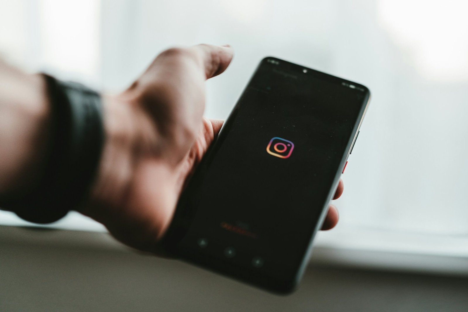 Mão segurando celular com o app do Instagram aberto, ilustrando como deixar o Instagram da empresa mais profissional